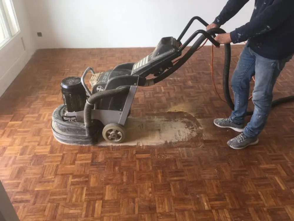 Profesional lijando un suelo de parquet con máquina acuchilladora